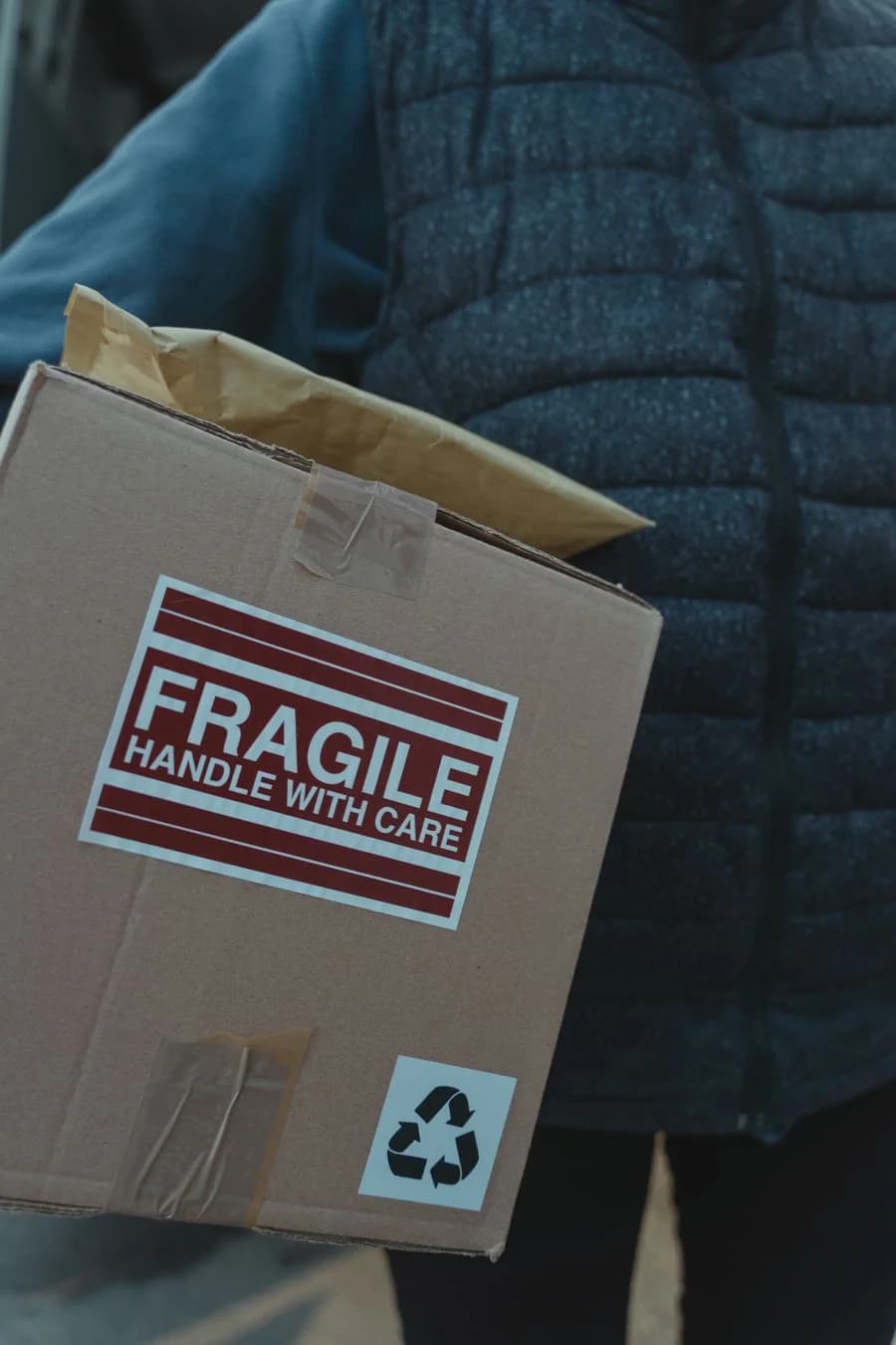 A delivery driver carrying a box marked fragile