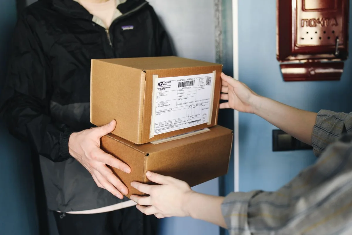 A courier handing two parcels to a customer at the door