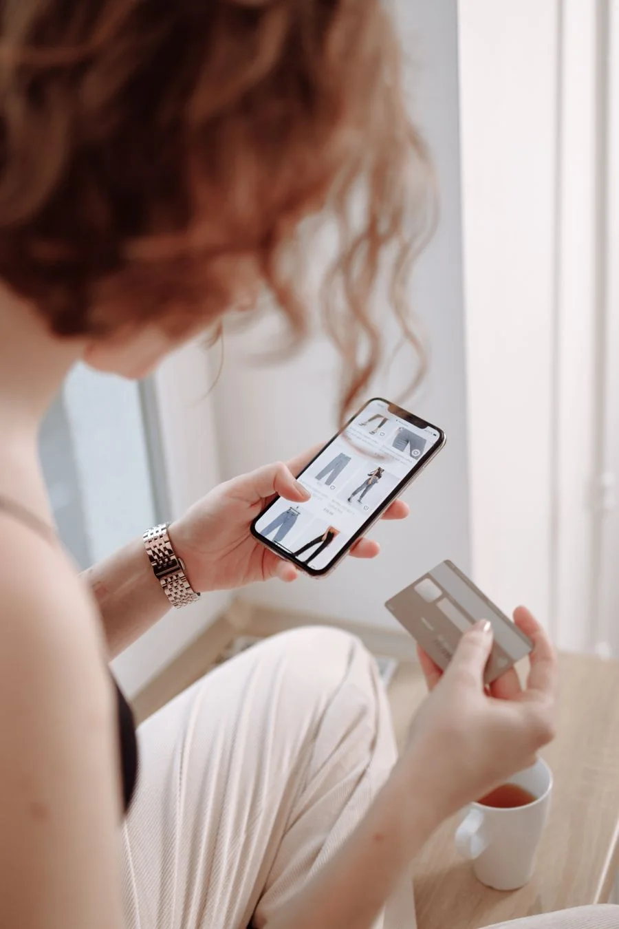 A shopper browsing clothes in an app, card in hand